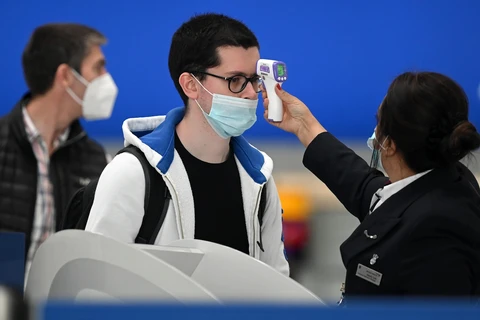 Kiểm tra thân nhiệt phòng lây nhiễm COVID-19 tại sân bay Heathrow ở London, Anh. (Ảnh: AFP/TTXVN)
