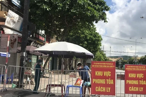 Người dân trong khu vực phong tỏa trên phố Ngô Quyền (Hải Dương) nhận thực phẩm tiếp tế tại hàng rào cách ly. (Ảnh: Mạnh Minh/TTXVN)