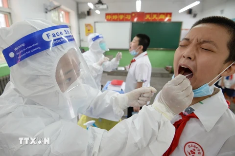Nhân viên y tế lấy mẫu dịch xét nghiệm COVID-19 cho học sinh tại một trường tiểu học ở Hàm Đan, tỉnh Hà Bắc, Trung Quốc ngày 17/8. (Ảnh: AFP/TTXVN)