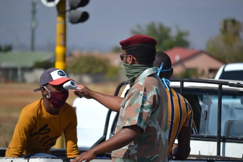 Binh lính Nam Phi kiểm tra thân nhiệt cho một người dân tại ngoại ô thủ đô Pretoria, Nam Phi. (Ảnh: Phi Hùng/TTXVN)