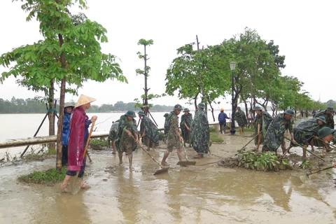 Các lực lượng dọn dẹp bùn đất tại khu vực 2 bên bờ sông Hương. (Ảnh: Tường Vi/TTXVN)