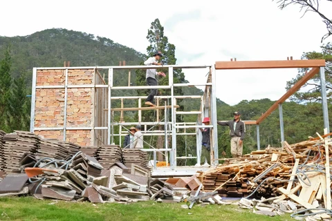Lực lượng chức năng tháo dỡ phần mái của các công trình xây dựng trái phép tại tiểu khu 268. (Ảnh: Nguyễn Dũng/TTXVN)
