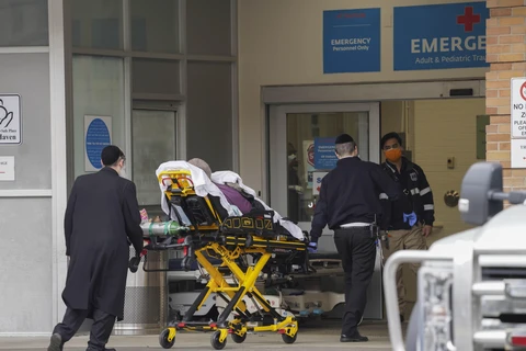 Nhân viên y tế chuyển bệnh nhân mắc COVID-19 vào một bệnh viện ở New York, Mỹ. (Ảnh: THX/TTXVN)