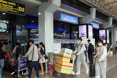 Để phòng chống dịch, nhiều hành khách đã chủ động trang bị các bộ đồ bảo hộ khi đến sân bay Tân Sơn Nhất. (Ảnh: Tiến Lực/TTXVN)
