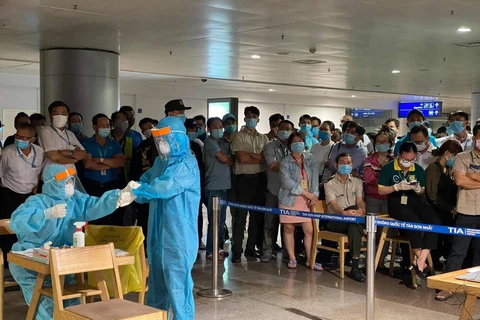 Nhân viên y tế làm thủ tục lấy mẫu xét nghiệm cho người làm việc tại sân bay Tân Sơn Nhất. (Ảnh: TTXVN phát)