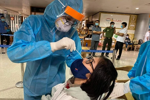 Nhân viên y tế lấy mẫu xét nghiệm cho người làm việc tại sân bay Tân Sơn Nhất. (Ảnh: TTXVN phát)