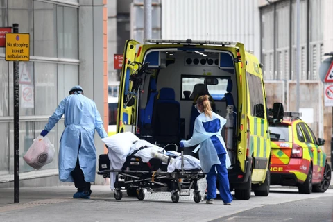 Nhân viên y tế chuyển bệnh nhân COVID-19 tới bệnh viện ở London, Anh. (Ảnh: AFP/TTXVN)