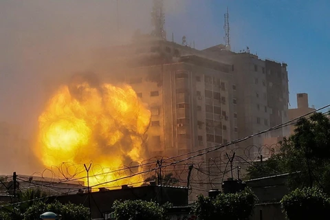 Khói lửa bốc lên từ Toà tháp Jala, nơi đặt văn phòng một số hãng truyền thông quốc tế, khi tòa nhà này bị trúng không kích của Israel tại Dải Gaza. (Ảnh: AFP/TTXVN)