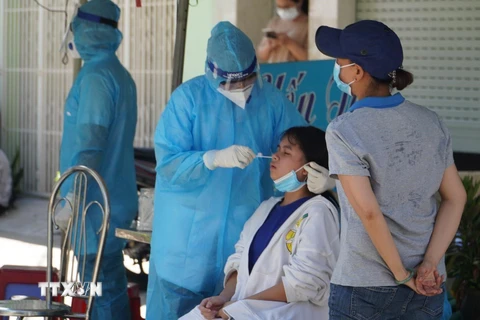 Lực lượng y tế tiến hành lấy mẫu xét nghiệm người dân trong hẻm bị phong tỏa. (Ảnh: TTXVN phát)