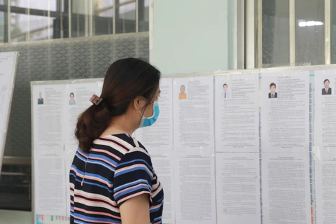 Cử tri tại Khu cách ly tập trung tại Trung tâm Y tế quận Gò Vấp nghiên cứu thông tin người ứng cử. (Ảnh: Đinh Hằng/TTXVN)