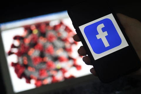 Biểu tượng mạng xã hội Facebook và virus corona trên màn hình điện thoại. (Ảnh: AFP/TTXVN)