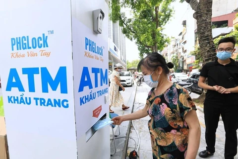 Người dân đến nhận khẩu trang từ cây ATM phát khẩu trang miễn phí trên phố Lạc Trung, Hà Nội. (Ảnh: Thành Đạt/TTXVN)