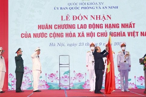 Chủ tịch nước Nguyễn Xuân Phúc gắn Huân chương Lao động hạng Nhất lên cờ truyền thống của Ủy ban Quốc phòng và An ninh của Quốc hội. (Ảnh: Doãn Tấn/TTXVN)