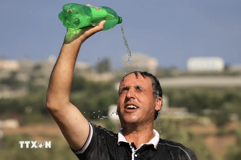 Một người đàn ông dội nước lên đầu làm mát dưới thời tiết nắng nóng tại Dải Gaza ngày 19/7/2023. (Ảnh: AFP/TTXVN)