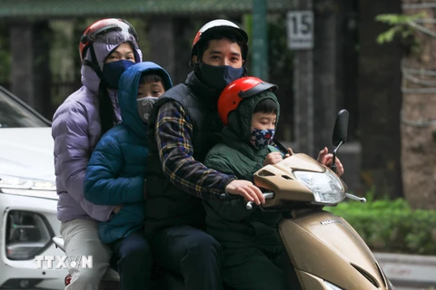 Một gia đình với trang phục ấm di chuyển trên phố Trần Hưng Đạo. (Ảnh: Hoàng Hiếu/TTXVN)