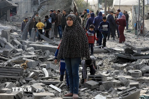 Người dân Palestine bên đống đổ nát của những tòa nhà bị phá hủy sau các cuộc không kích của Israel tại thành phố Rafah, Dải Gaza ngày 12/2/2024. (Ảnh: THX/TTXVN)