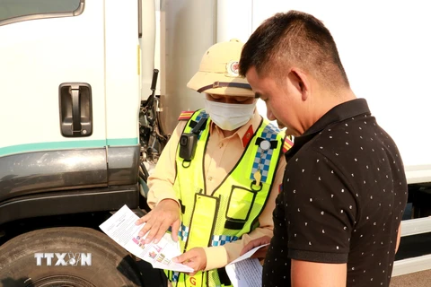 Cảnh sát giao thông tuyên truyền cho lái xe đi vào cao tốc Cam Lộ-La Sơn được an toàn tại điểm đầu ở xã Cam Hiếu, huyện Cam Lộ (Quảng Trị). (Ảnh: Nguyên Lý/TTXVN)