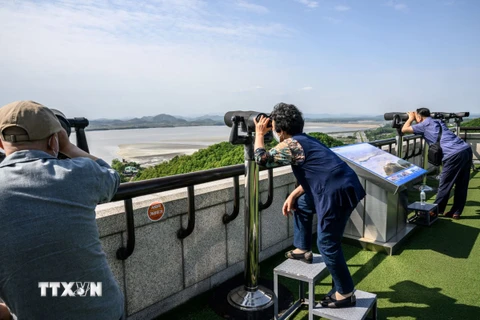 Khách du lịch quan sát bằng ống nhòm Khu phi quân sự (DMZ) liên Triều từ Đài quan sát Odusan ở Paju, Hàn Quốc, ngày 12/5/2022. (Ảnh: AFP/TTXVN)