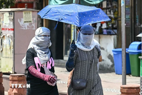 Người dân di chuyển dưới trời nắng nóng tại New Delhi, Ấn Độ. (Ảnh: AFP/TTXVN)