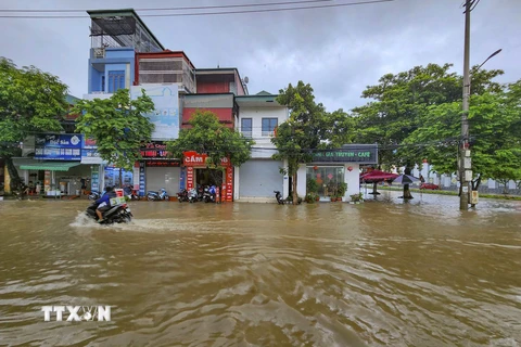 Nước ngập sâu khiến cho các phương tiện giao thông đi lại khó khăn, ảnh hưởng đến sinh hoạt của người dân. (Ảnh: Xuân Tư/TTXVN)