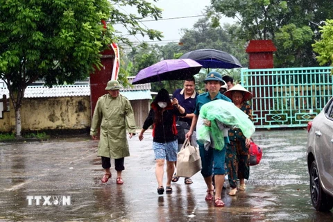 Cán bộ chính quyền địa phương hộ trợ người dân di dời trước nguy cơ sạt lở núi cây Sường (thị trấn Quy Đạt, huyện Minh Hóa). (Ảnh: Tá Chuyên/TTXVN)