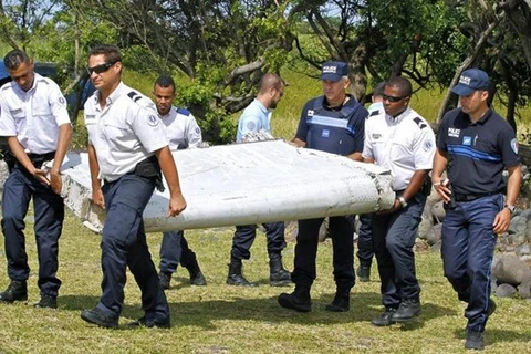 Các nhân viên điều tra mang mảnh vỡ máy bay trôi dạt vào đảo Reunion. (Nguồn: AP) 