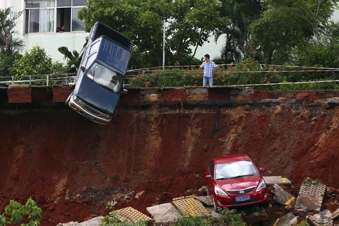 Một người đàn ông ở Hải Khẩu, tỉnh Hải Nam, Trung Quốc nhìn vào chiếc xe bị mắc kẹt trong 'hố tử thần' với ánh mắt vô vọng. (Nguồn: Reuters)