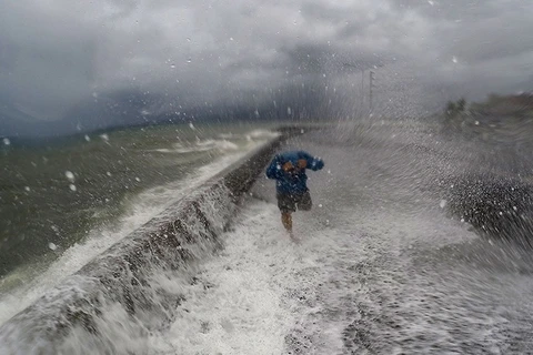Một người dân ở huyện Albay cố chạy khỏi những con sóng do bão Melor gây ra. (Nguồn: AFP)