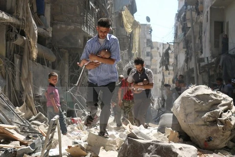 Chuyển các em nhỏ Syria ra khỏi một tòa nhà bị sập sau vụ không kích nhằm vào khu vực Salihin ở thành phố Aleppo, miền Bắc Syria ngày 11/9. (Nguồn: AFP/TTXVN)