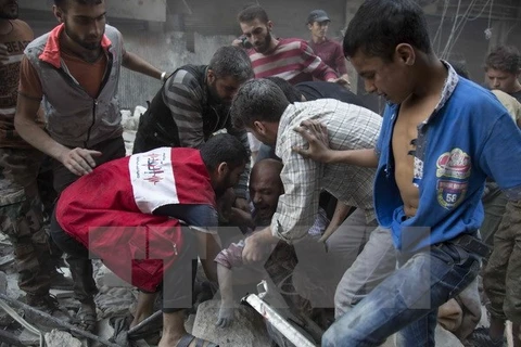 Một người đàn ông đau khổ sau khi tìm thấy xác con dưới những đống đổ nát sau các vụ không kích tại Aleppo ngày 27/9. (Nguồn: AFP/TTXVN)