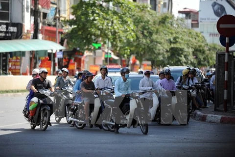 Người dân chen chân trong bóng mát khi chờ đèn xanh giao thông tại Hà Nội. (Ảnh: Quang Quyết/TTXVN)