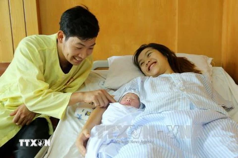 Vợ chồng sản phụ Phạm Thị Hồng Loan hạnh phúc bên cháu bé. (Ảnh: Trung Kiên/TTXVN) 