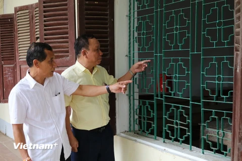Ông Khamphanh (phải) hào hứng kể lại cho người bạn Thongdeng về chỗ ngồi ở ngôi trường cũ năm xưa họ từng học. (Ảnh: Huy Đồng/Vietnam+)