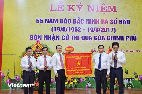 Thừa ủy quyền của Thủ tướng Chính phủ, ông Nguyễn Nhân Chiến - Bí thư tỉnh ủy Bắc Ninh trao cờ của Chính phủ cho ban lãnh đạo Báo Bắc Ninh. (Ảnh: Thanh Thương/Vietnam+)