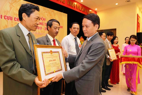 Đồng chí Nguyễn Đức Lợi, Tổng Giám đốc TTXVN trao bằng khen cho các Cựu Chiến binh TTXVN. (Ảnh: TTXVN)