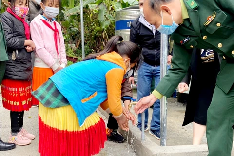 Cán bộ Đồn Biên phòng Lũng Cú hướng dẫn các em học sinh sử dụng công trình nước sạch. (Ảnh: CTV/Vietnam+)