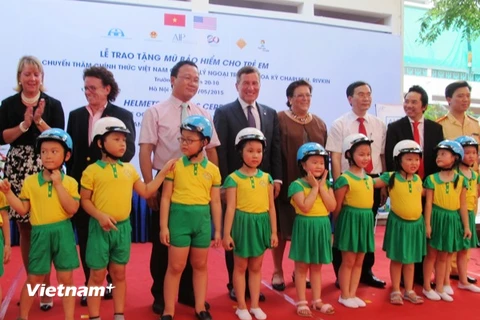 Các đại biểu đội mũ an toàn giao thông cho trẻ em để bảo vệ tính mạng. (Ảnh: Việt Hùng/Vietnam+)