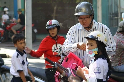 Phụ huynh mua mũ bảo hiểm chuẩn cho trẻ khi tham gia giao thông. (Ảnh: PV/Vietnam+)