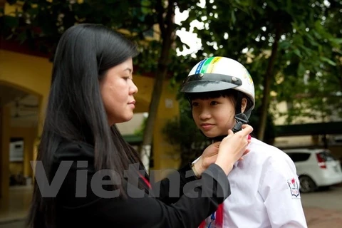 Trẻ em đội mũ an toàn giao thông để bảo vệ tính mạng. (Ảnh: Việt Hùng/Vietnam+)
