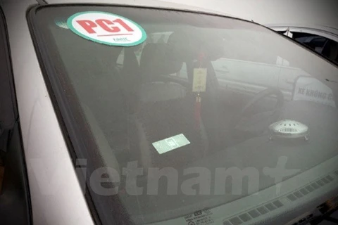 Thẻ E-tag (hình chữ nhật) được dán trên kính xe phía bên trái của tài xế điều khiển, tính phí tự động với trạm thu phí theo công nghệ không dừng. (Ảnh: Việt Hùng/Vietnam+).