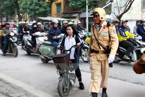 Cảnh sát giao thông xử lý vi phạm học sinh điều khiển xe đạp máy, xe đạp điện không đội mũ bảo hiểm. (Ảnh: Doãn Tấn/TTXVN)
