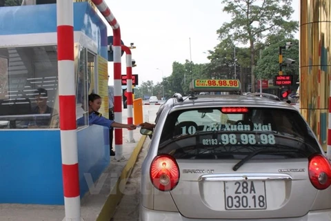 Chủ phương tiện mua vé đường bộ tại trạm thu phí Quốc lộ 6 đoạn Xuân Mai-Hòa Bình. (Ảnh: Việt Hùng/Vietnam+)