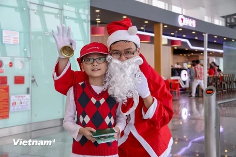 Hành khách nhí chụp hình và nhận món quà từ Ông già Noel của Cảng hàng không Nội Bài. (Ảnh: Dương Phạm/Vietnam+)