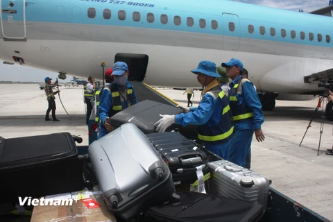 Nhân viên bốc xếp hành lý ký gửi từ hầm hàng máy bay lên xe vận chuyển. (Ảnh: Việt Hùng/Vietnam)