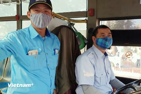 Tài xế và nhân viên bán vé xe buýt của Tổng công ty Vận tải Hà Nội đã đeo khẩu trang trong quá trình phục vụ vận tải hành khách. (Ảnh: CTV/Vietnam+)