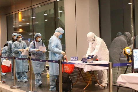 Công dân Việt Nam được hướng dẫn khử trùng trước khi làm thủ tục nhập cảnh tại sân bay Vân Đồn (Quảng Ninh).(Ảnh: Dương Giang/TTXVN)