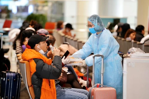 Nhân viên của Cảng hàng không phục vụ suất ăn và nước uống miễn phí đối với những hành khách đang chờ làm thủ tục y tế và đi đến điểm cách ly theo đúng quy định. (Ảnh: CTV/Vietnam+)
