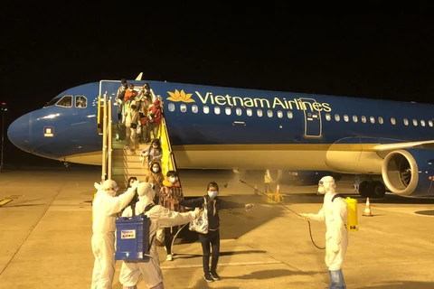 Phun khử khuẩn toàn bộ hành khách sau khi bước xuống máy bay và sau đó được đưa đi cách ly tập trung nhằm phòng chống COVID-19. (Ảnh: CTV/Vietnam+)