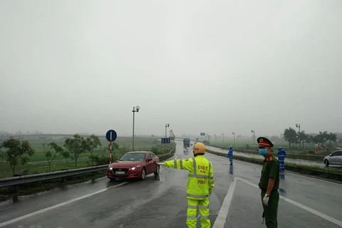 Lực lượng cảnh sát, công an đang túc trực để tuần tra, kiểm soát các phương tiện ra vào Thủ đô tại khu vực cầu Thụy Hương 1, Quốc lộ 18, huyện Sóc Sơn, Hà Nội. (Ảnh: PV/Vietnam+)