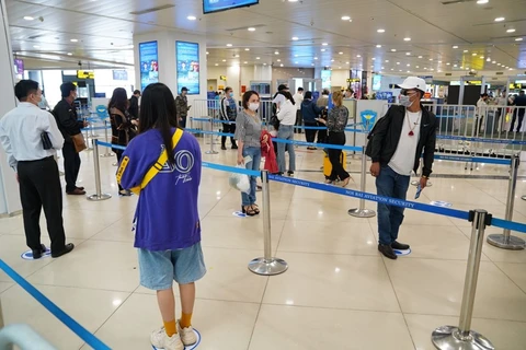 Hành khách tuân thủ khoảng cách tối thiểu khi làm thủ tục tại sân bay Nội Bài sau khi nới lỏng giãn cách xã hội. (Ảnh: Phan Công/Vietnam+)